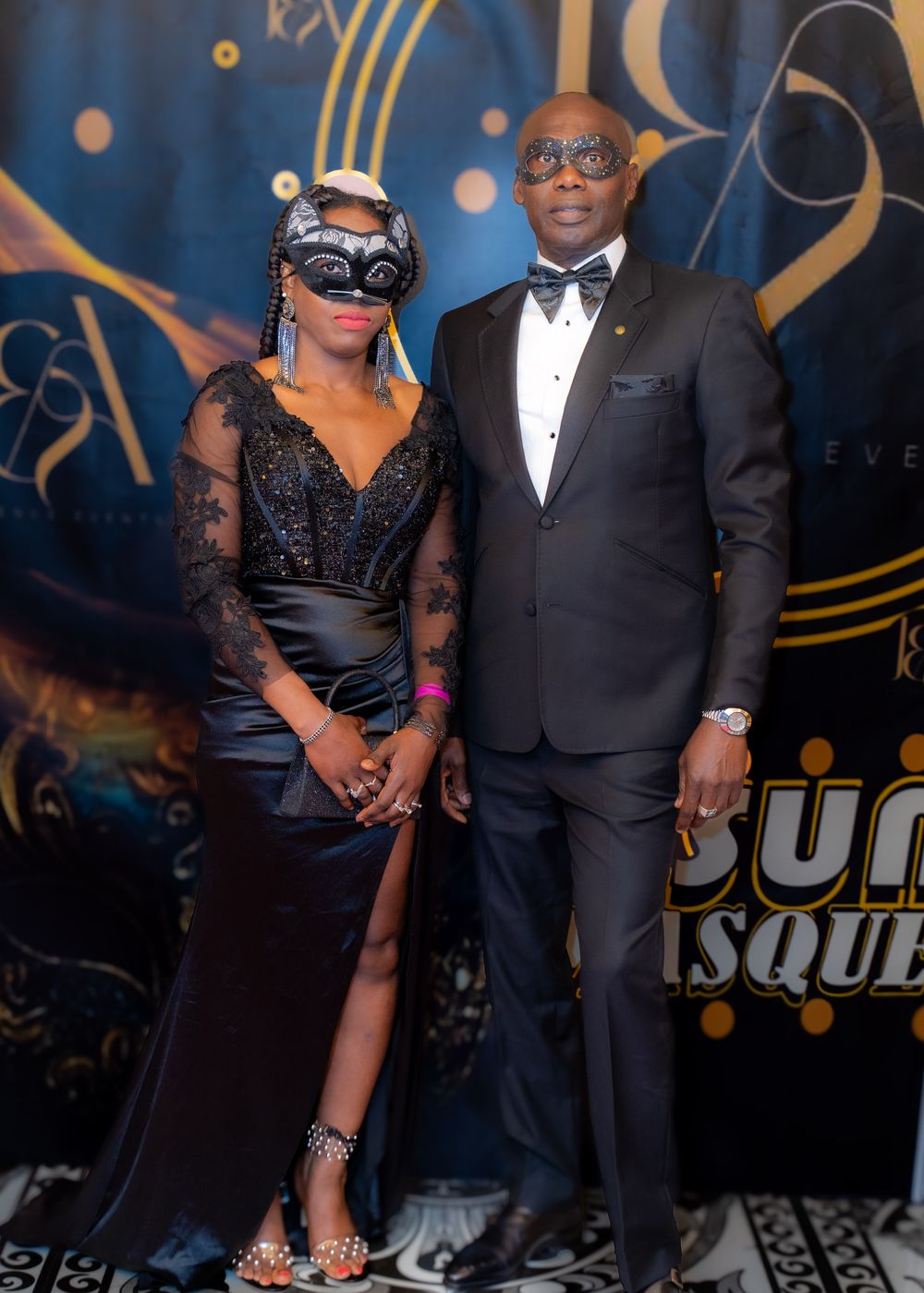 A couple in masquerade masks and black tie at the ball